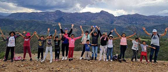 Children cheering in front of mountain range
